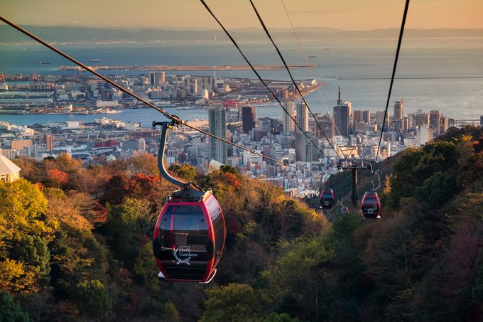 Kobe, Japan - November 25, 2016: Shin-Kobe Ropeway cable cars to Nunobiki Herb Garden with autumn foliage color and skyline city view at sunset.